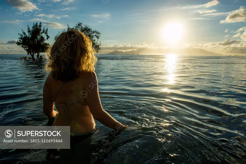 French Polynesia, Tahiti, Papeete, woman enjoying the sunset in an infinity pool