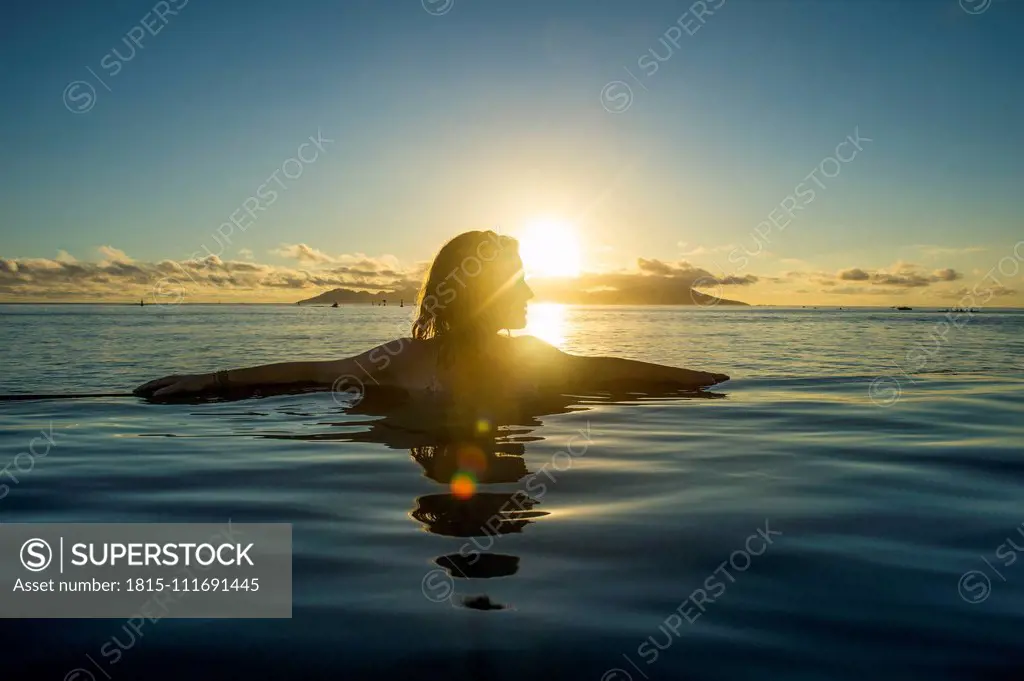 French Polynesia, Tahiti, Papeete, woman enjoying the sunset in an infinity pool