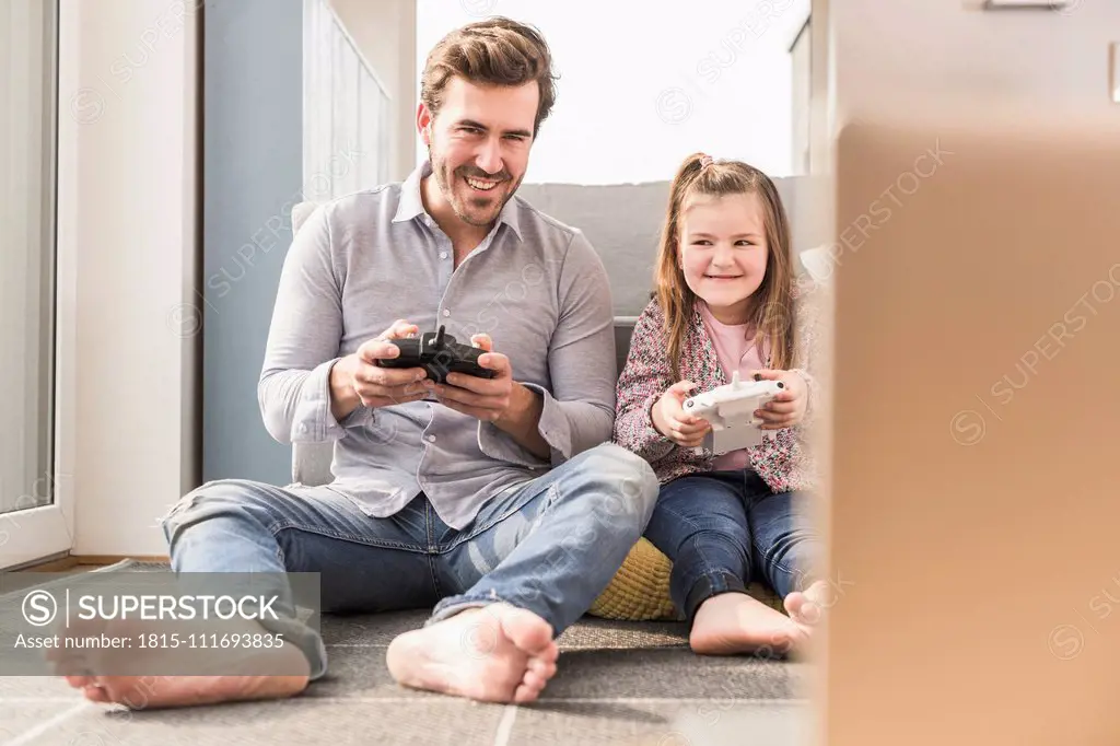 Young man and little girl playing computer game with gaming console