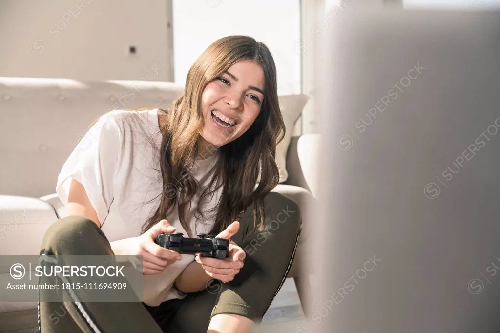 Happy young woman playing video game at home