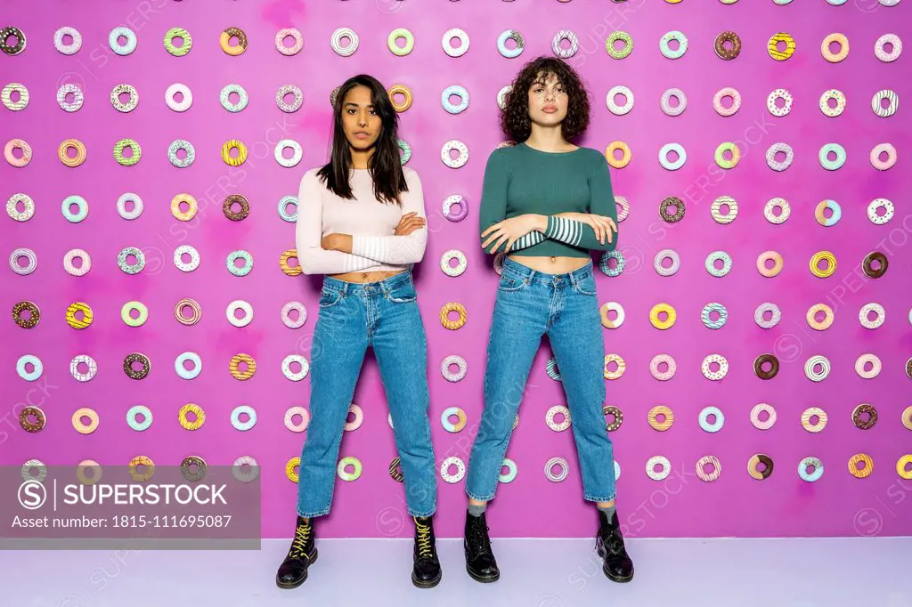 Two young women posing at an indoor theme park with donuts at the wall