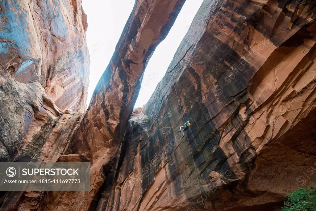 USA, Utah, Moab, Canyonering, Woman rapelling down a giant arch