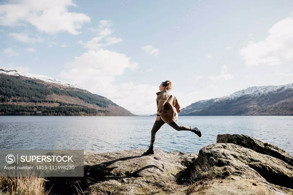 UK, Scotland, young woman running at Loch Lomond