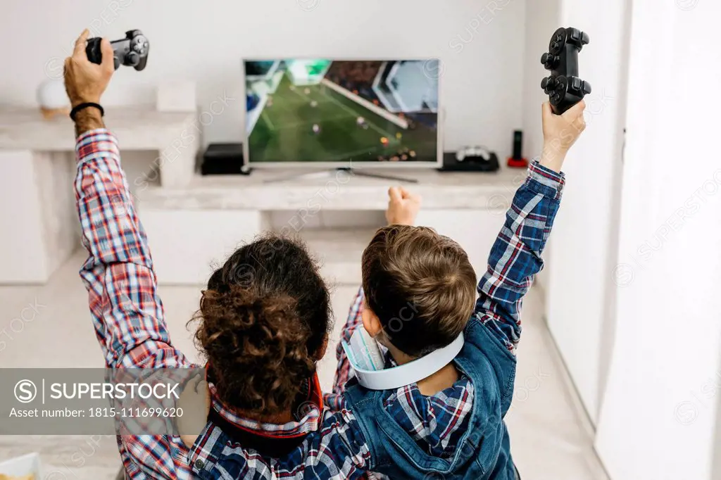 Father and son playing computer game at home