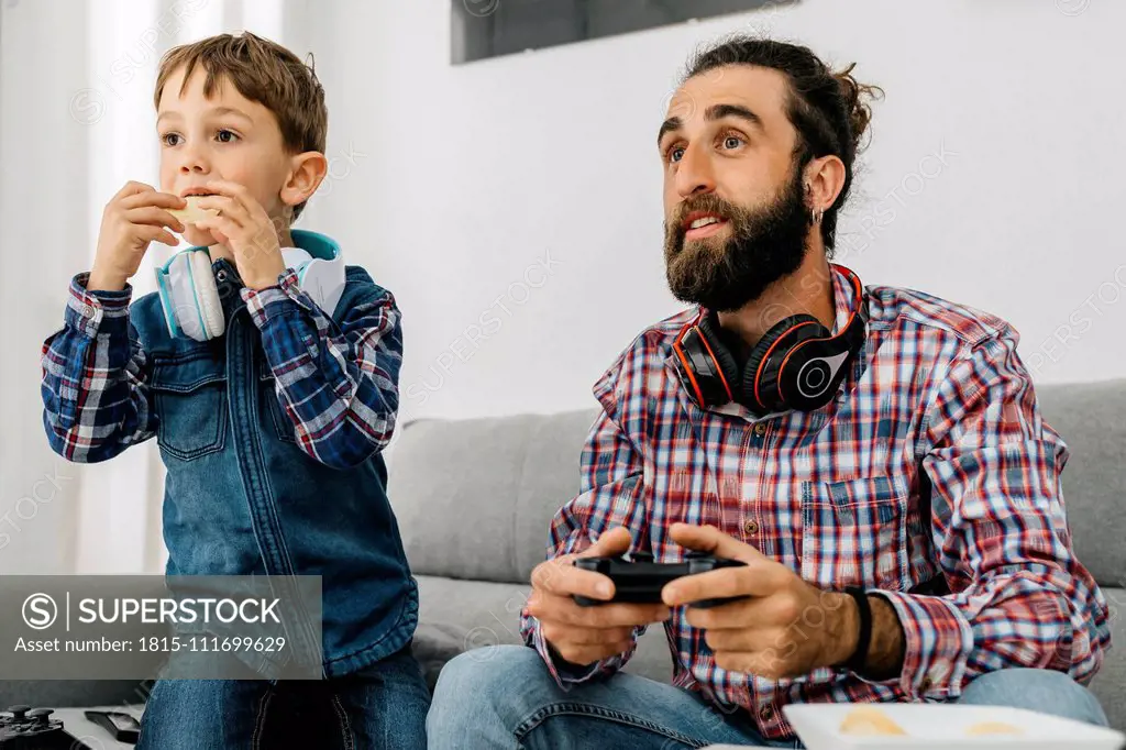 Portrait of father and son on the couch playing computer game