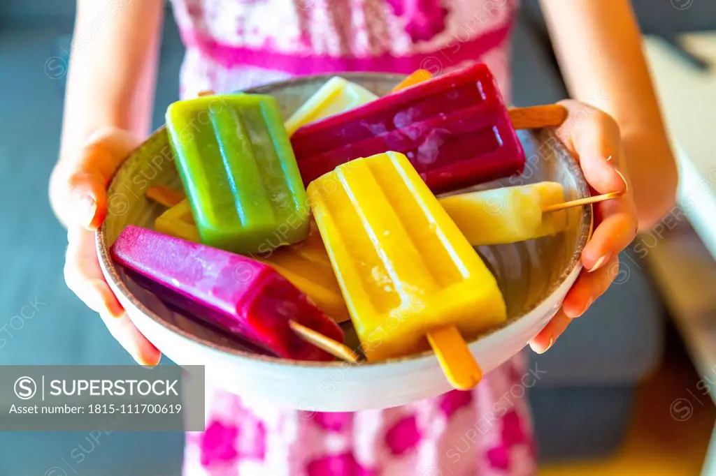 Girl holding bowl with colorful popsicles