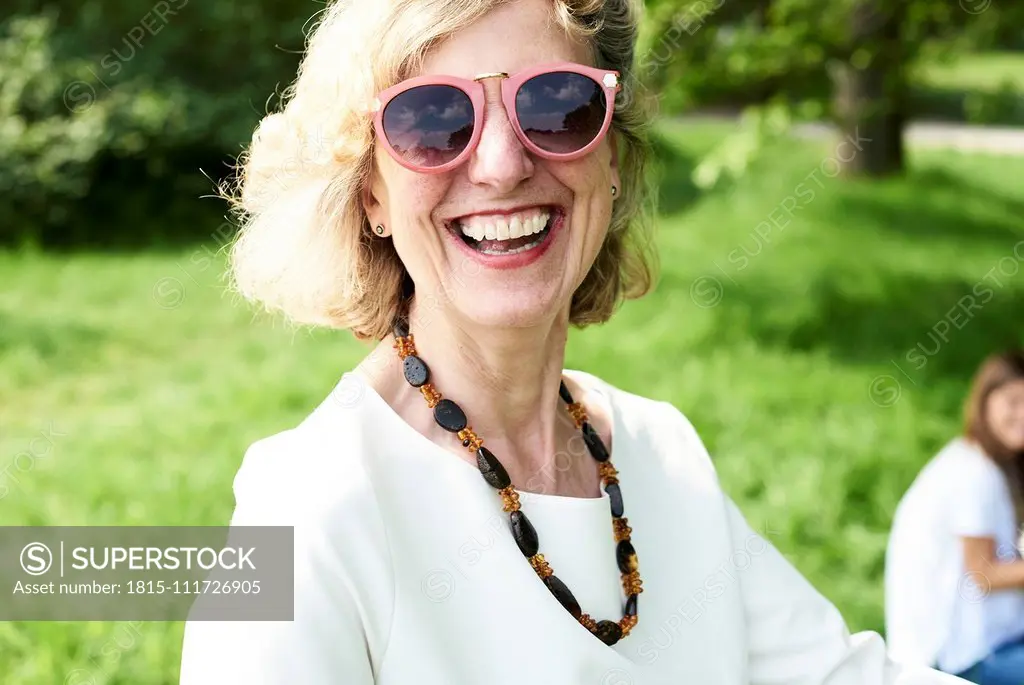 Portrait of happy senior woman wearing sunglasses in park