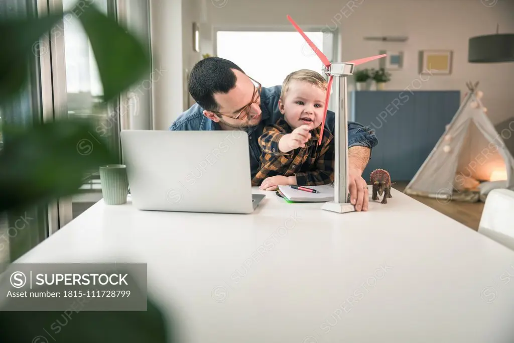 Father and son at home with wind turbine model on table