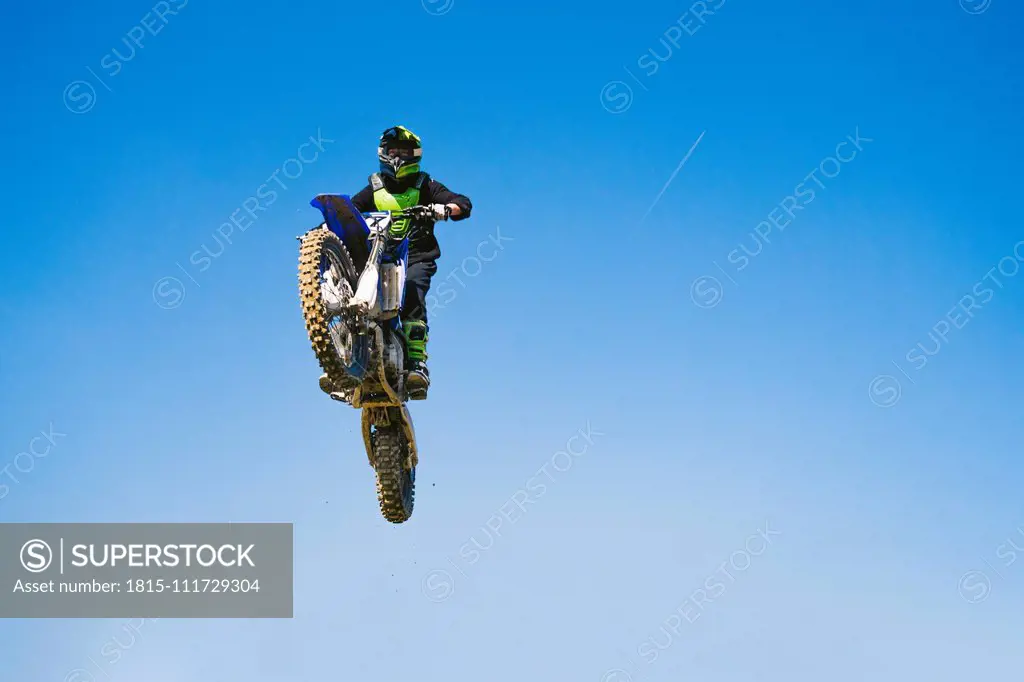 Motocross driver jumping in blue sky
