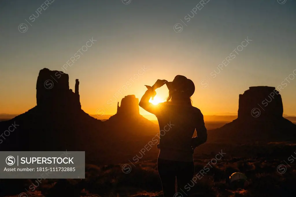 USA, Utah, Monument Valley, silhouette of woman with cowboy hat watching sunrise