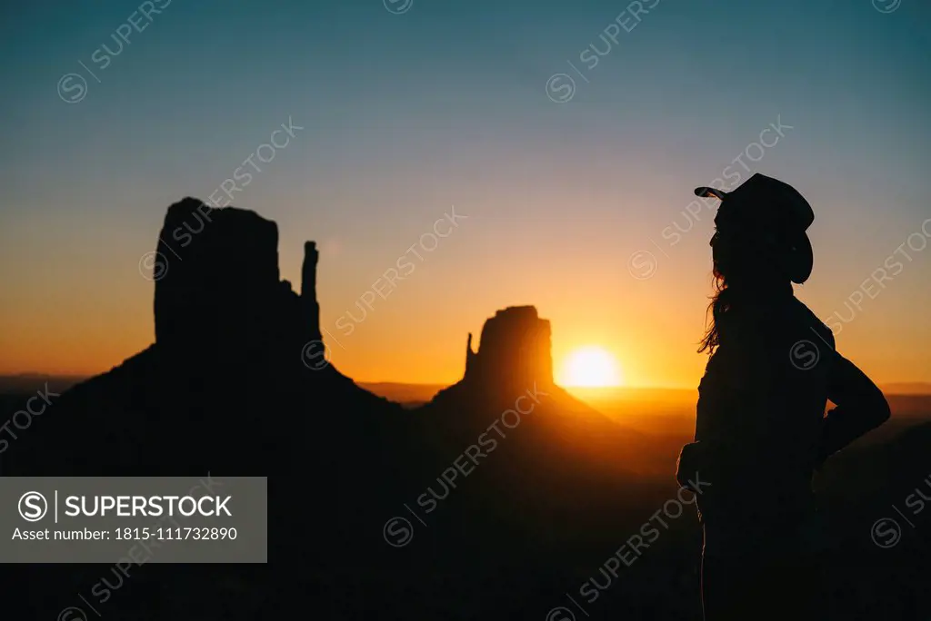 USA, Utah, Monument Valley, silhouette of woman with cowboy hat watching sunrise