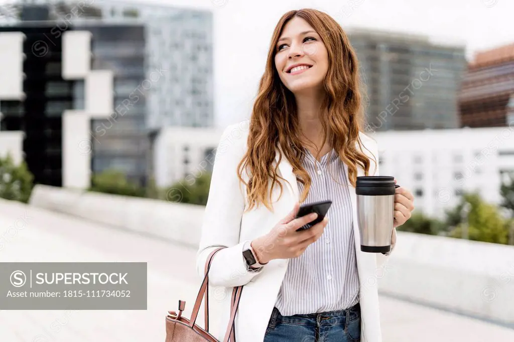 Young businesswoman commuting in the city, using smartphone