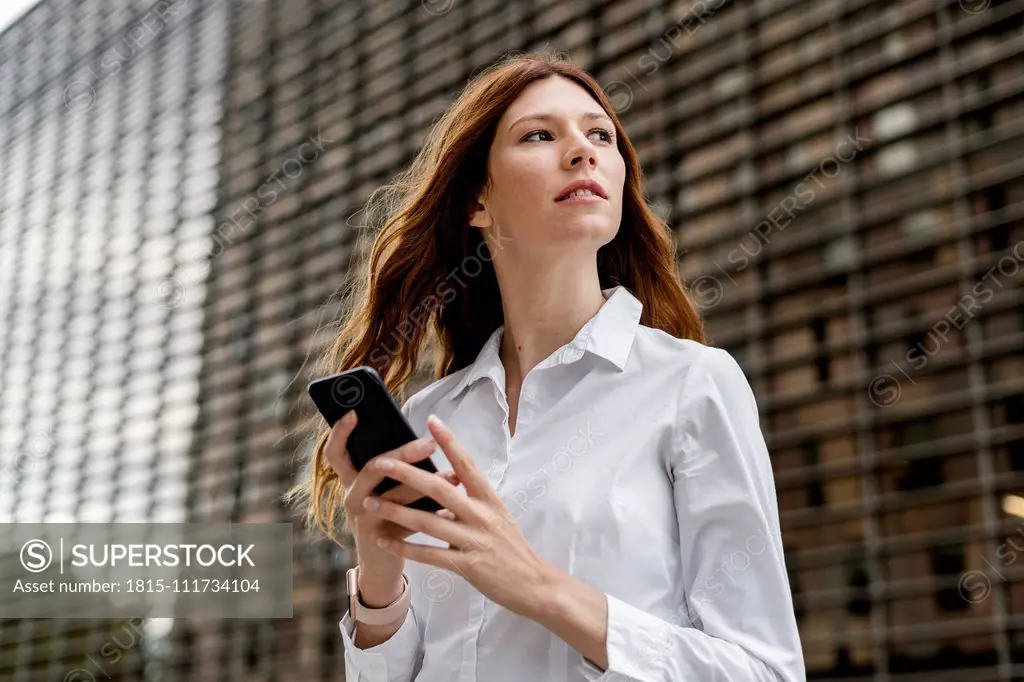 Young businesswoman in the city, using smartphone