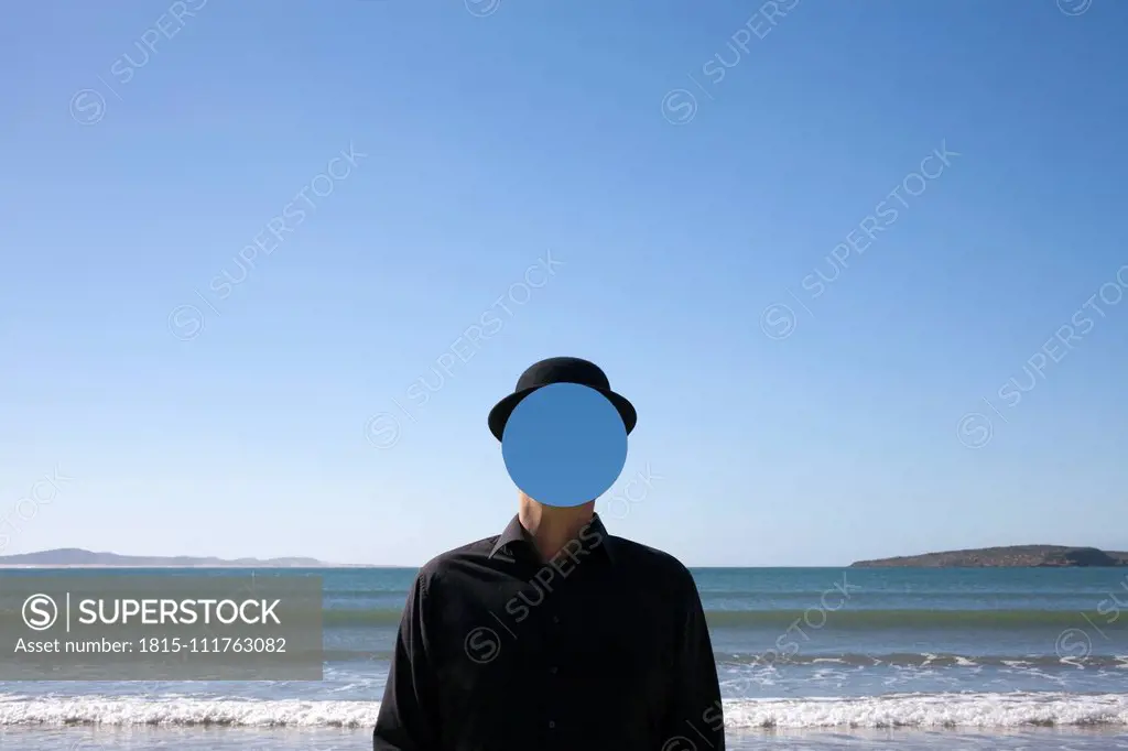 Morocco, Essaouira, man wearing a bowler hat with mirror in front of his face at the sea