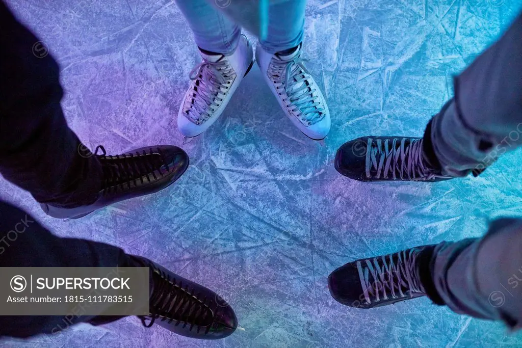 Legs of friends wearing ice skates standing on an ice rink