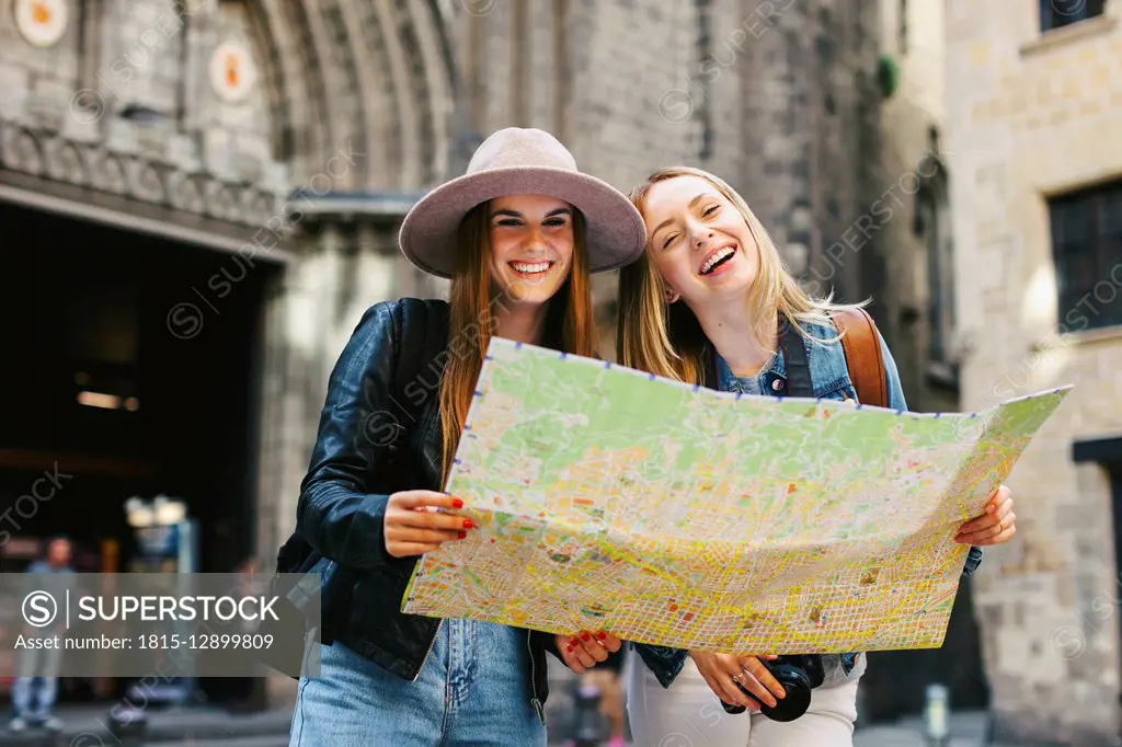 Spain, Barcelona, two happy young women reading map