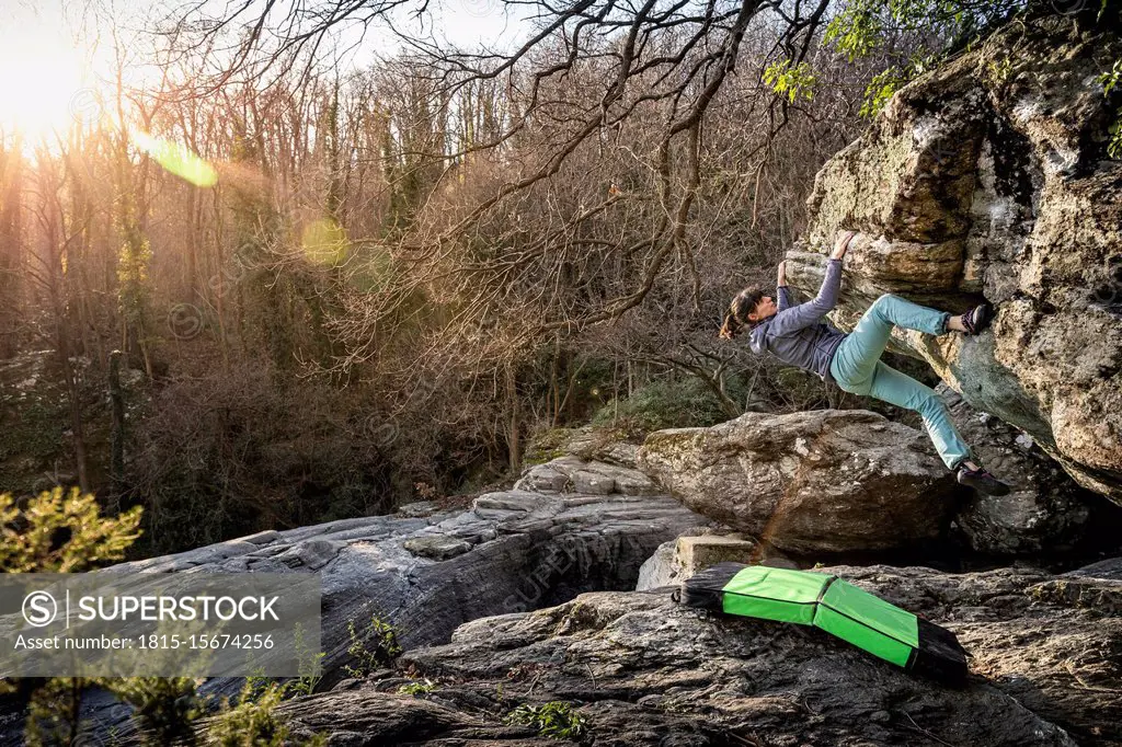 Woman bouldering in boulder area Varazze, Alpicella, Liguria, Italy