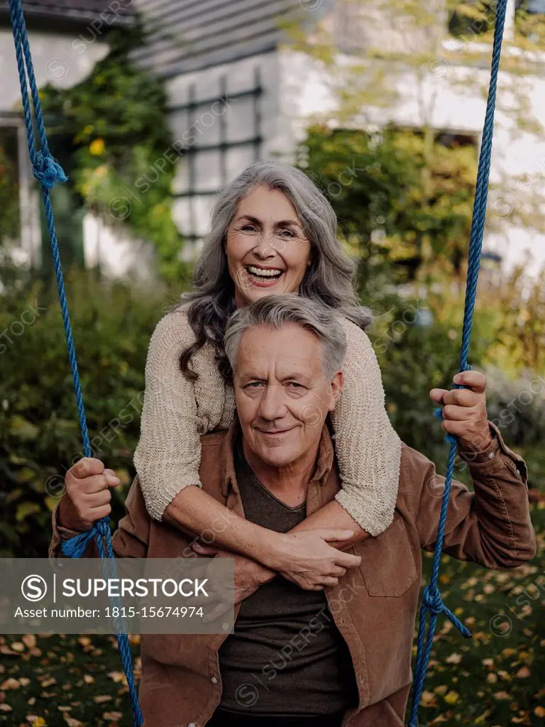 Happy woman embracing senior man on a swing in garden