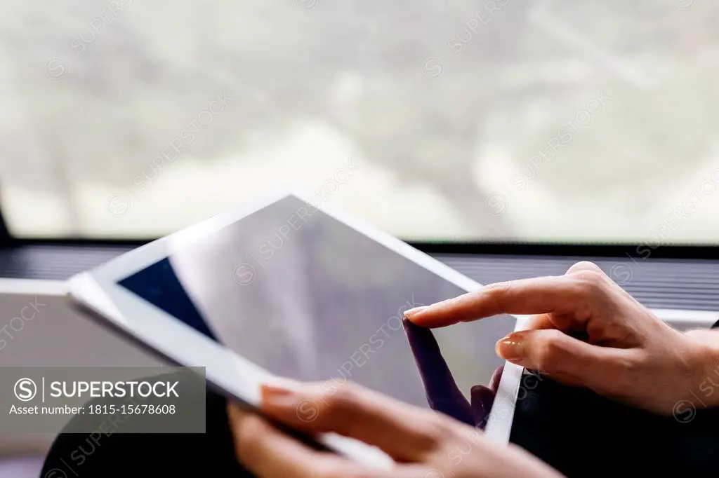 Woman's hand using a tablet while traveling by train