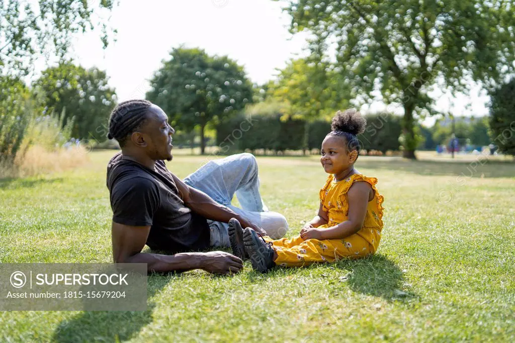 Father and daughter relaxing on a meadow in a park