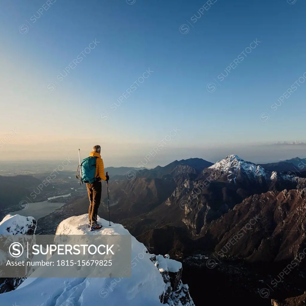 Mountaineer standing on top of a snowy mountain enjoying the view, Lecco, Italy