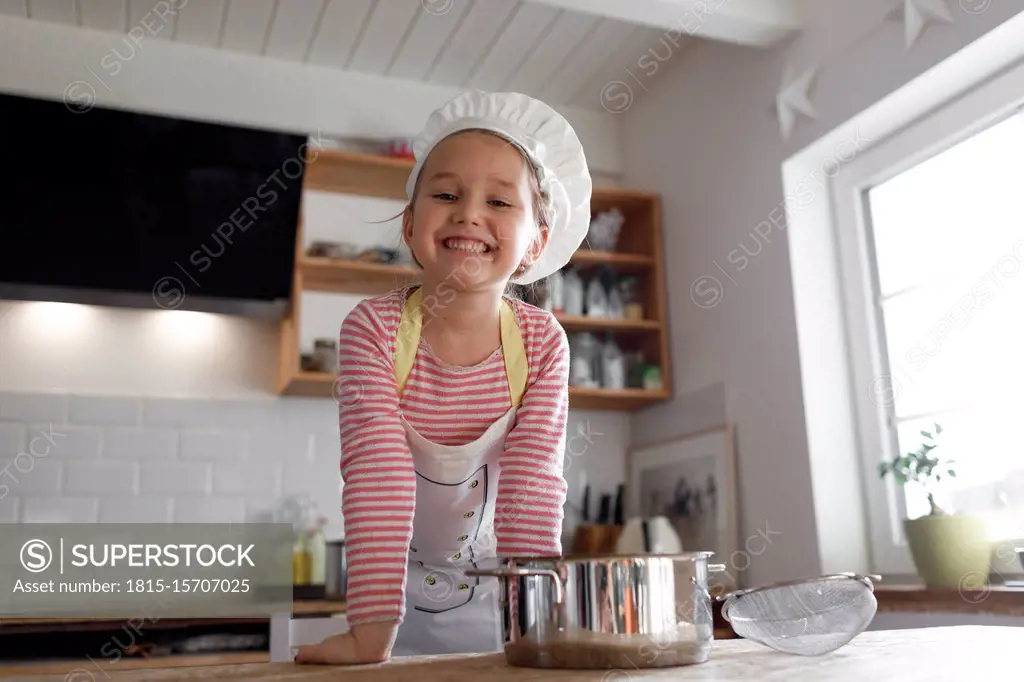 Portrait of smiling girl wearing chef's hat in the kitchen