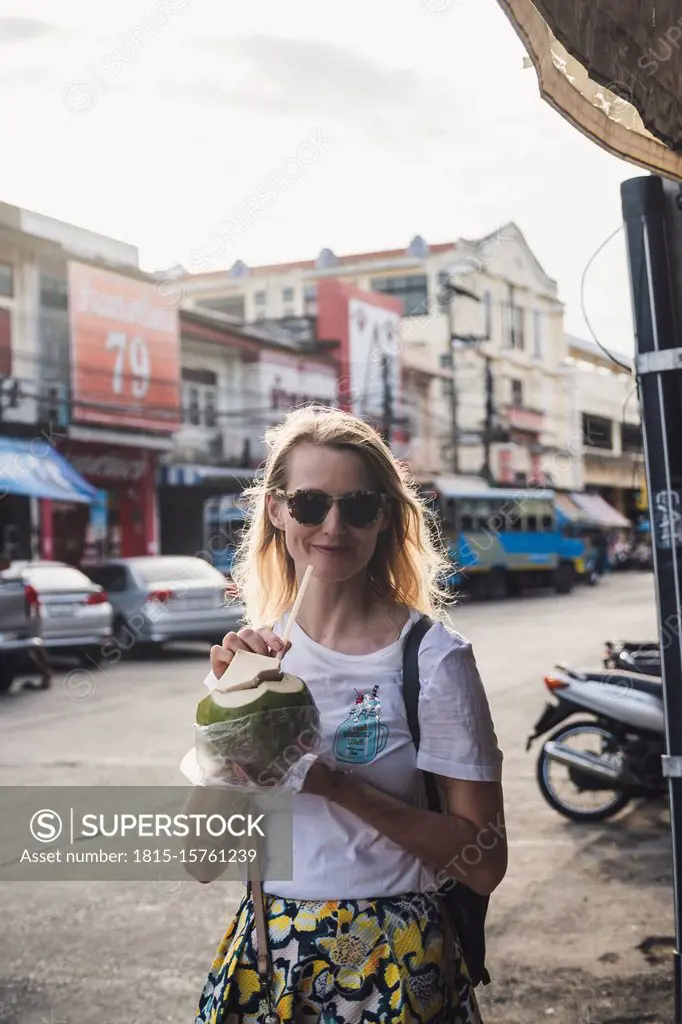 Portrait of smiling woman drinking from coconut, Old Town Phuket, Thailand