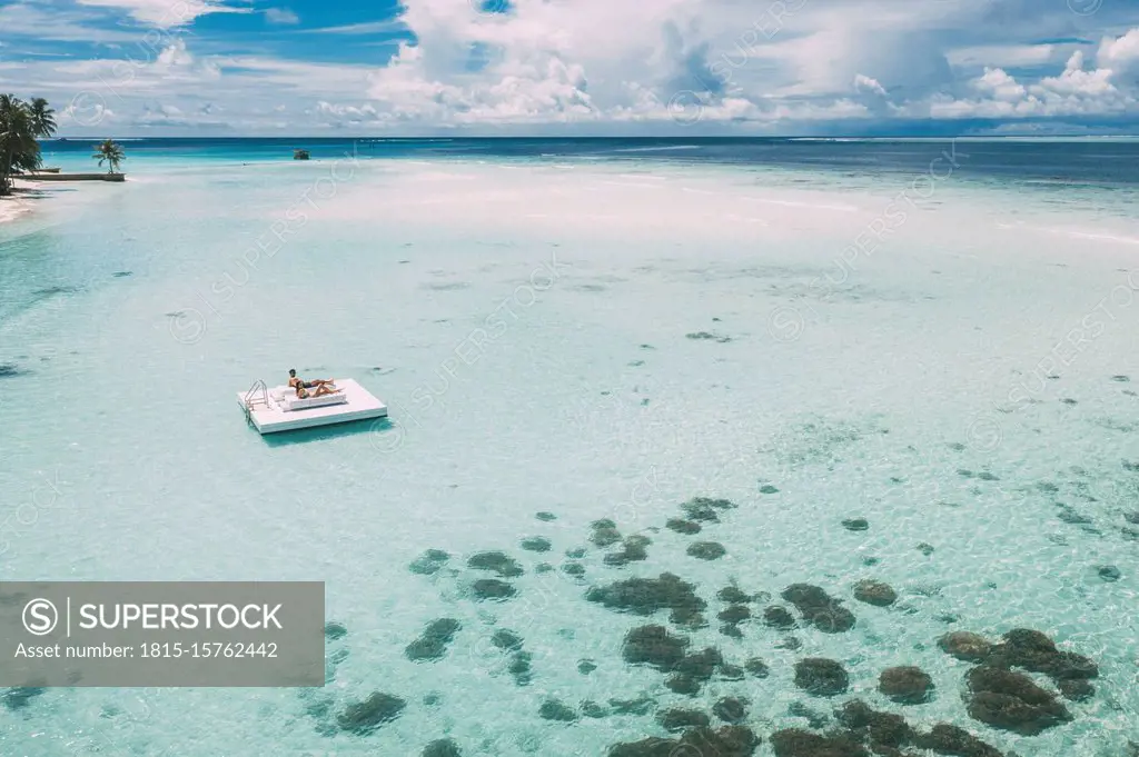 Couple lying on a platform in the sea, Maguhdhuvaa Island, Gaafu Dhaalu Atoll, Maldives