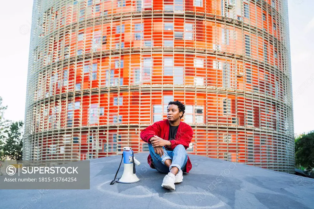 Portrait of mature man with megaphone sitting outdoors, Barcelona, Spain