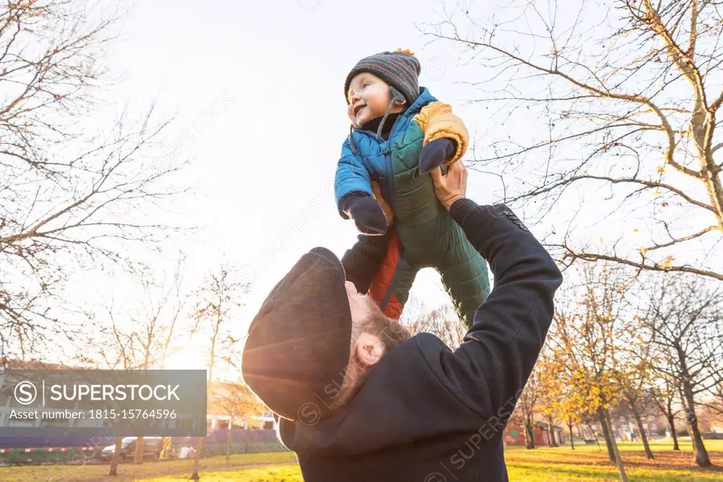 Man lifting up his happy baby son at park