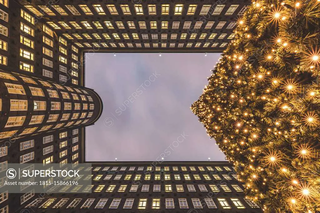 Germany, Hamburg, Directly below view of glowing Christmas tree and exterior of Sprinkenhof building