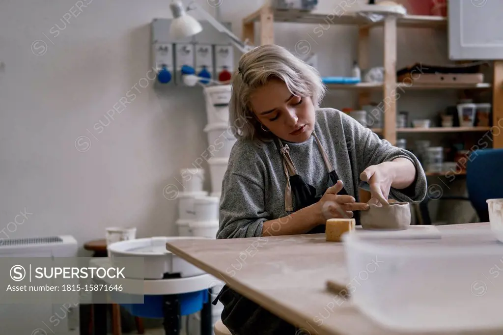 Young woman working on workpiece in pottery
