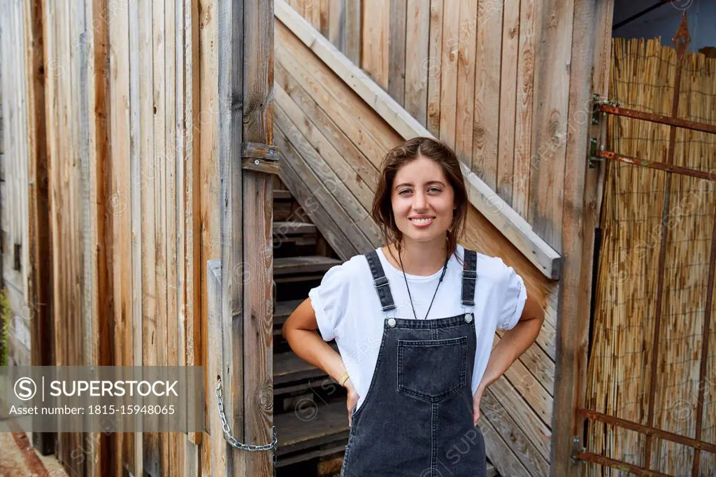 Portrait of smiling young woman in front of wooden fence