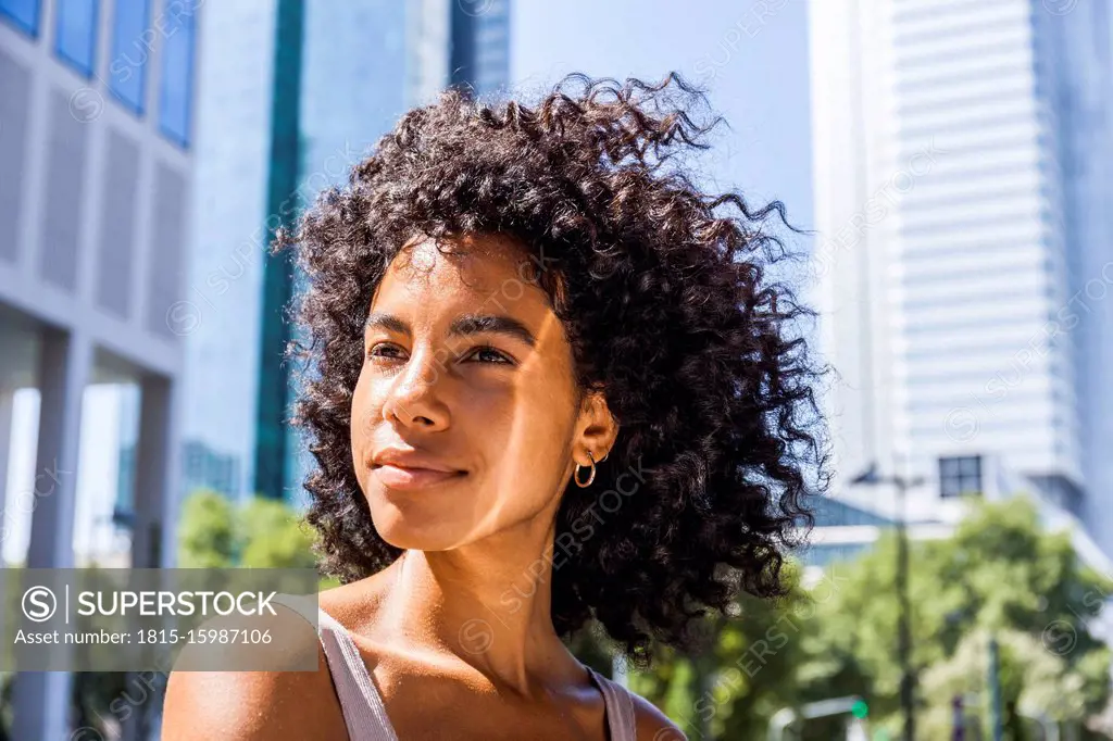 Germany, Frankfurt, portrait of content young woman with curly hair