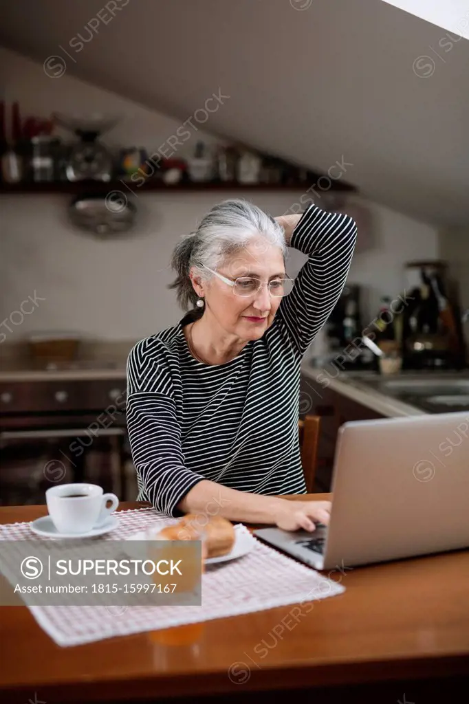 Portrait of senior woman using laptop at breakfast table