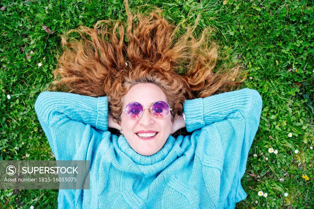 Portrait of happy redheaded mature woman lying on grass