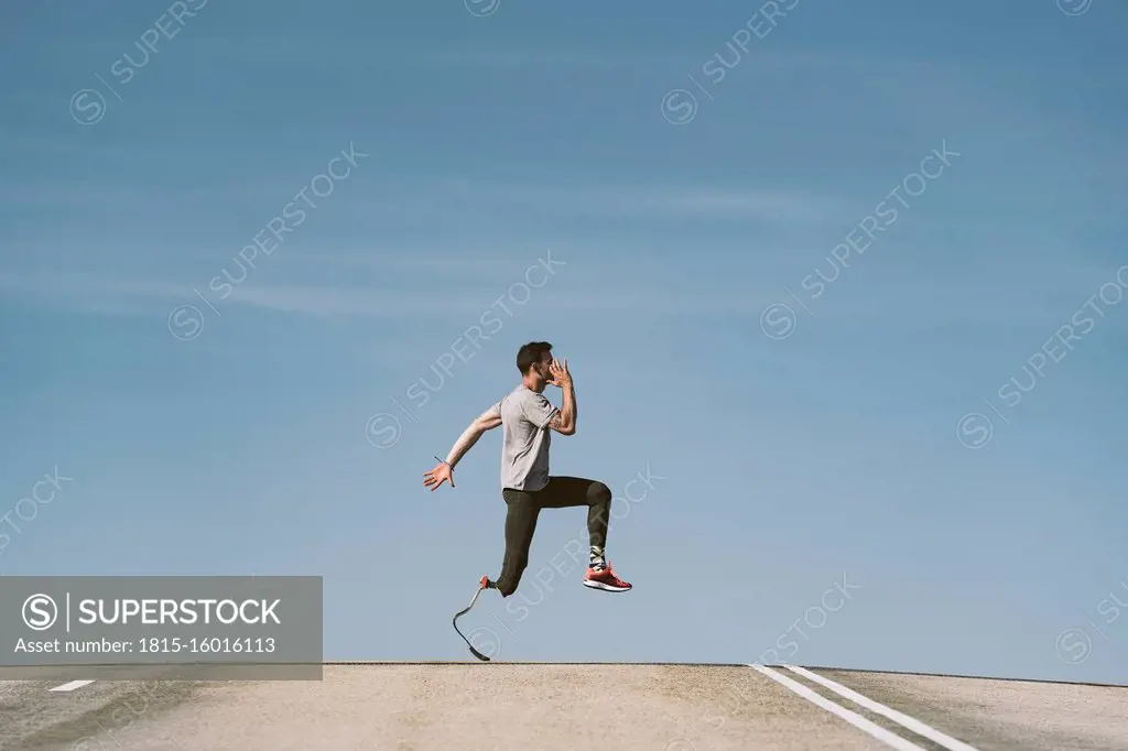 Disabled athlete with leg prosthesis exercising on a road