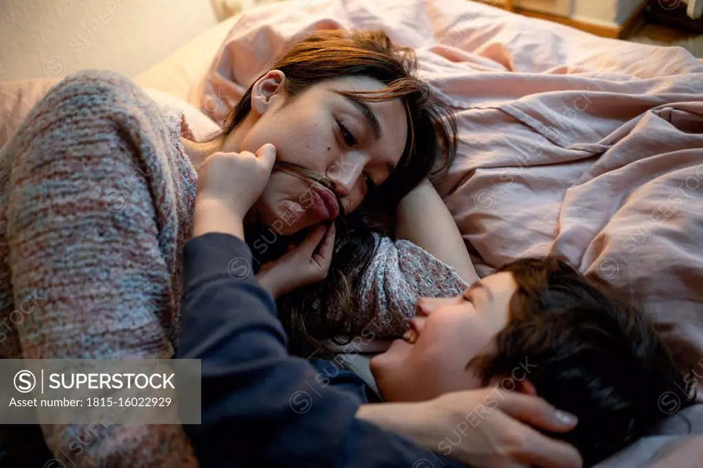 Mother and little son lying together on bed having fun