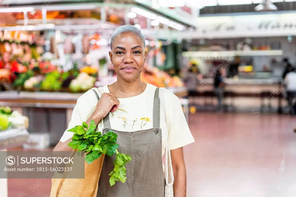 Portrait of smiling woman buying groceries in a market hall