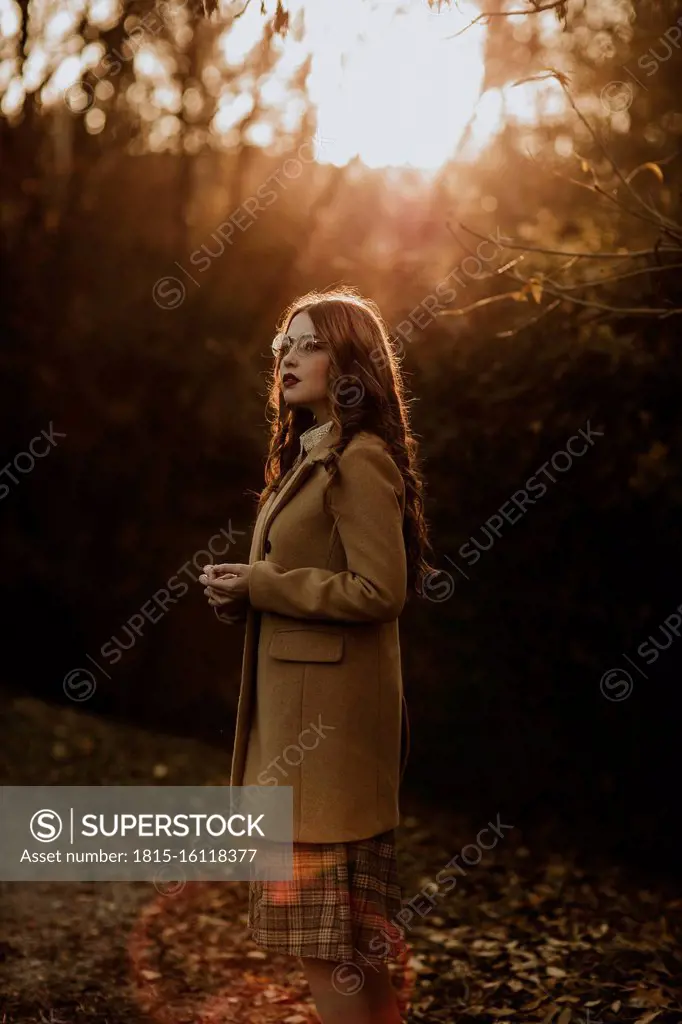 Portrait of fashionable woman in autumn standing at backlight