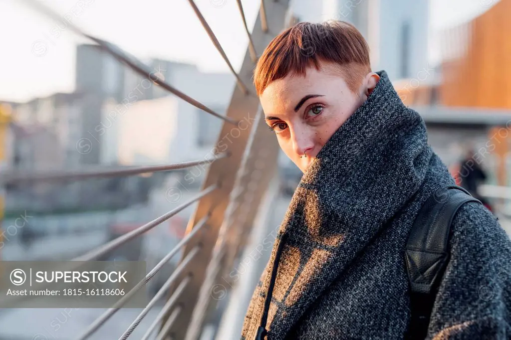 Portrait of redheaded young woman on a bridge in the city at sunset