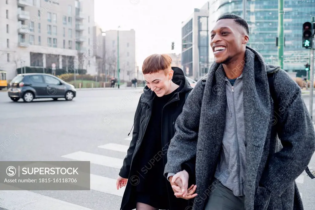 Happy young couple crossing a street in the city, Milan, Italy