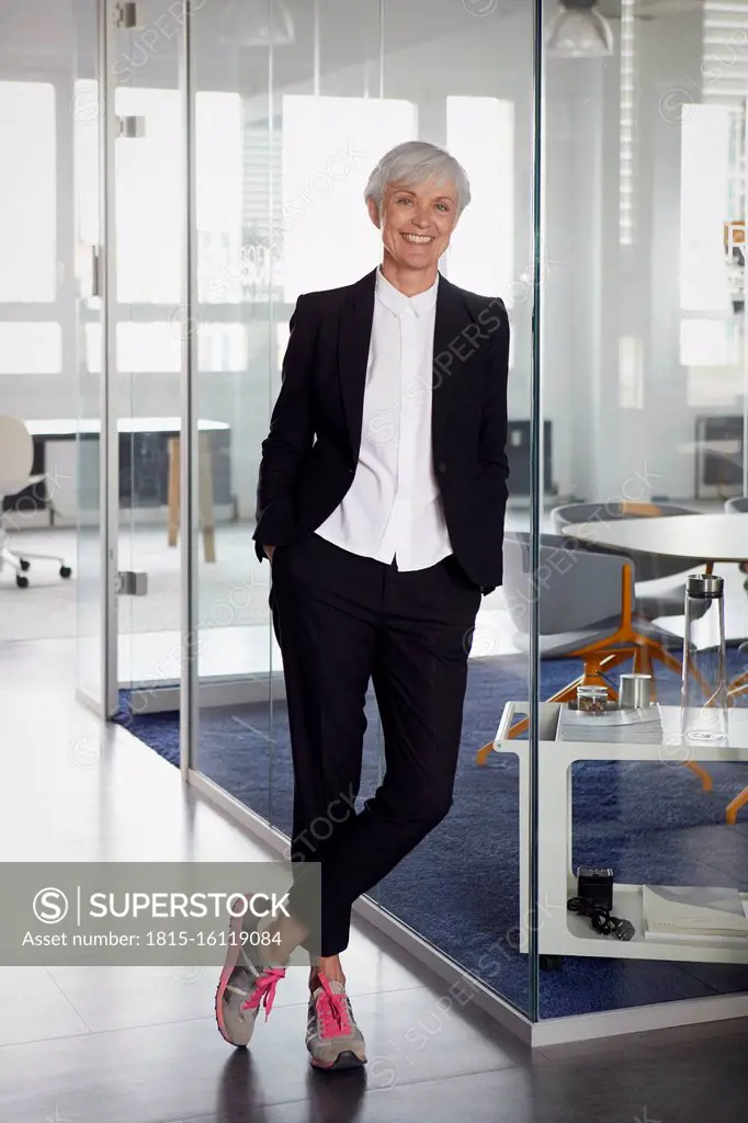 Portrait of fashionable senior businesswoman wearing pantsuit and sneakers in office