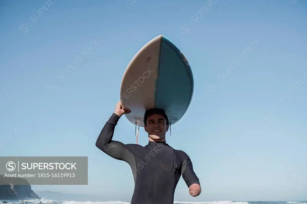 Handicapped surfer carrying his surfboard on head