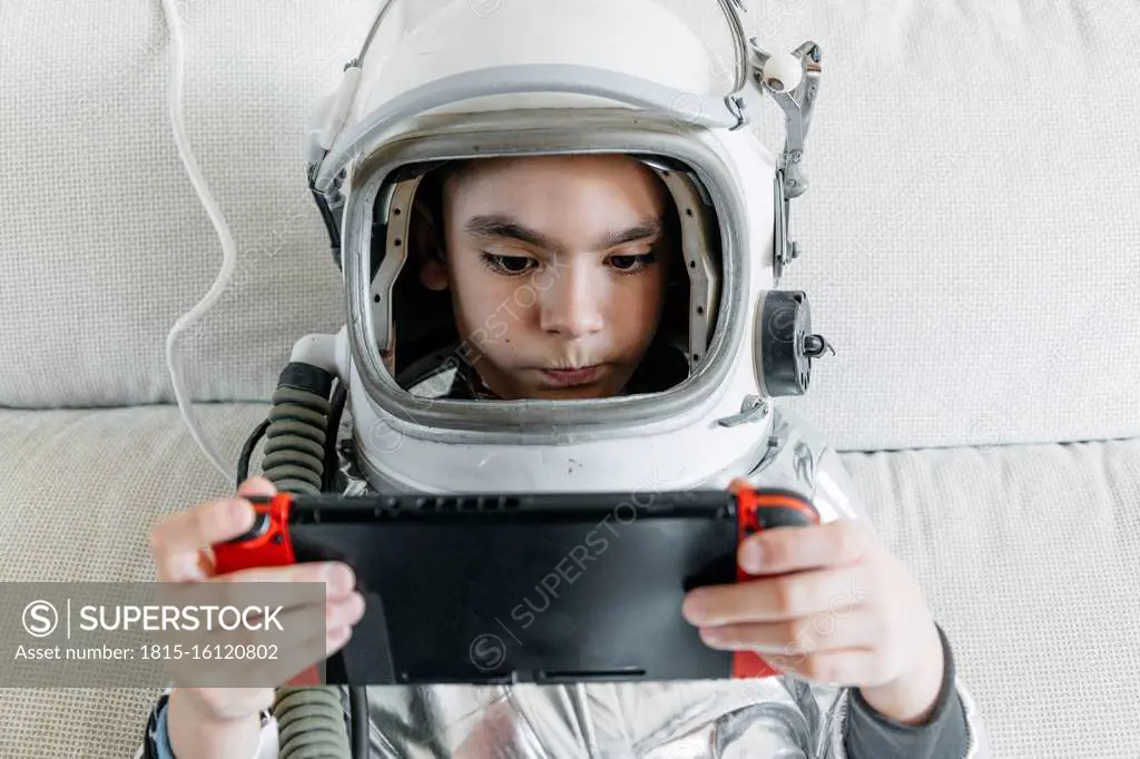 Boy playing video game on a games console, wearing space hat