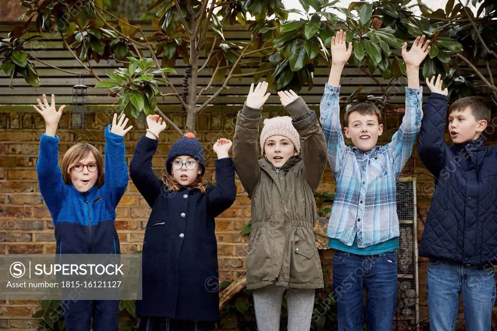 Group of children on the schoolyard raising their arms during break time