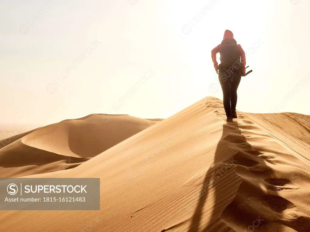 Woman walking on the ridge of a dune in the desert, Walvis Bay, Namibia