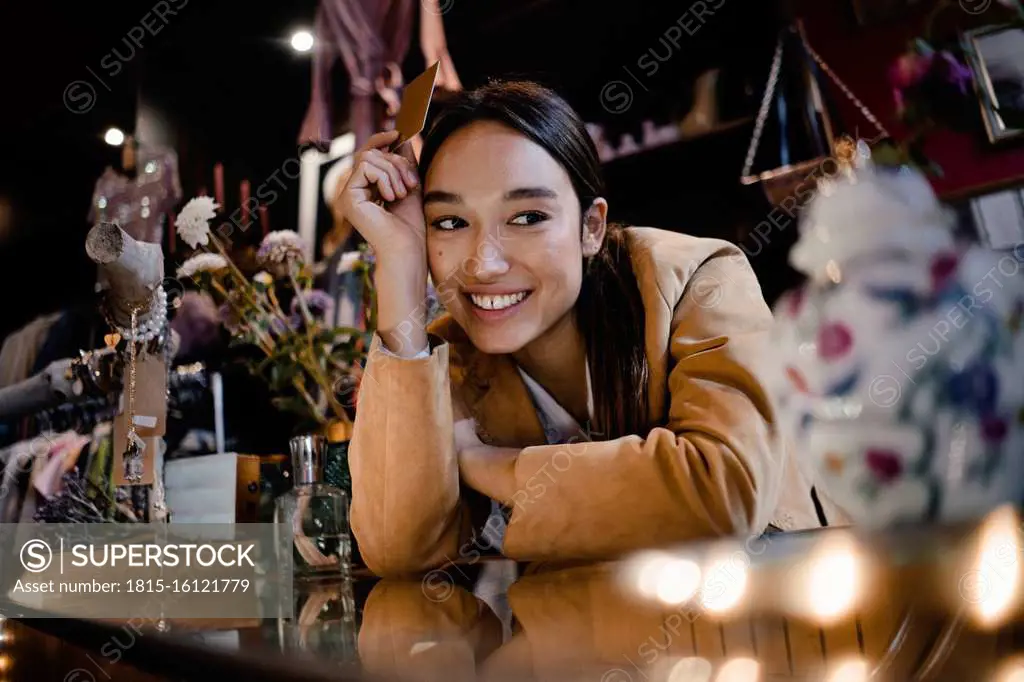 Thoughtful smiling customer with credit card leaning at checkout counter