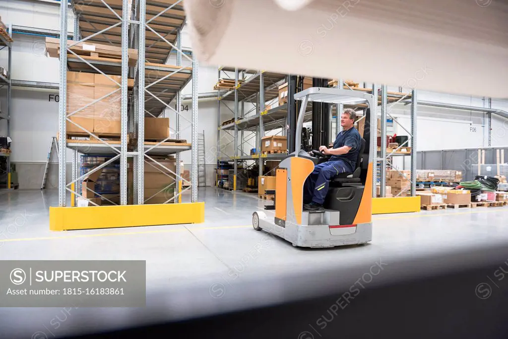 Worker on forklift in high rack warehouse