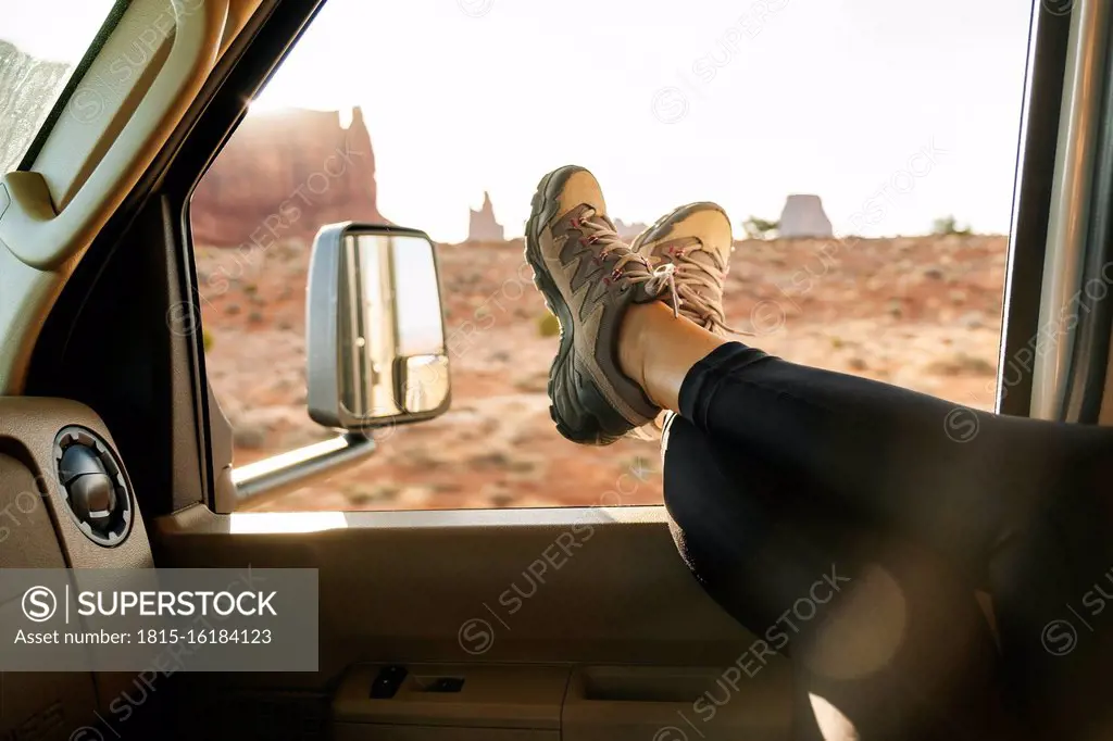 Low section of woman relaxing with feet up on vehicle window, Monument Valley Tribal Park, Utah, USA